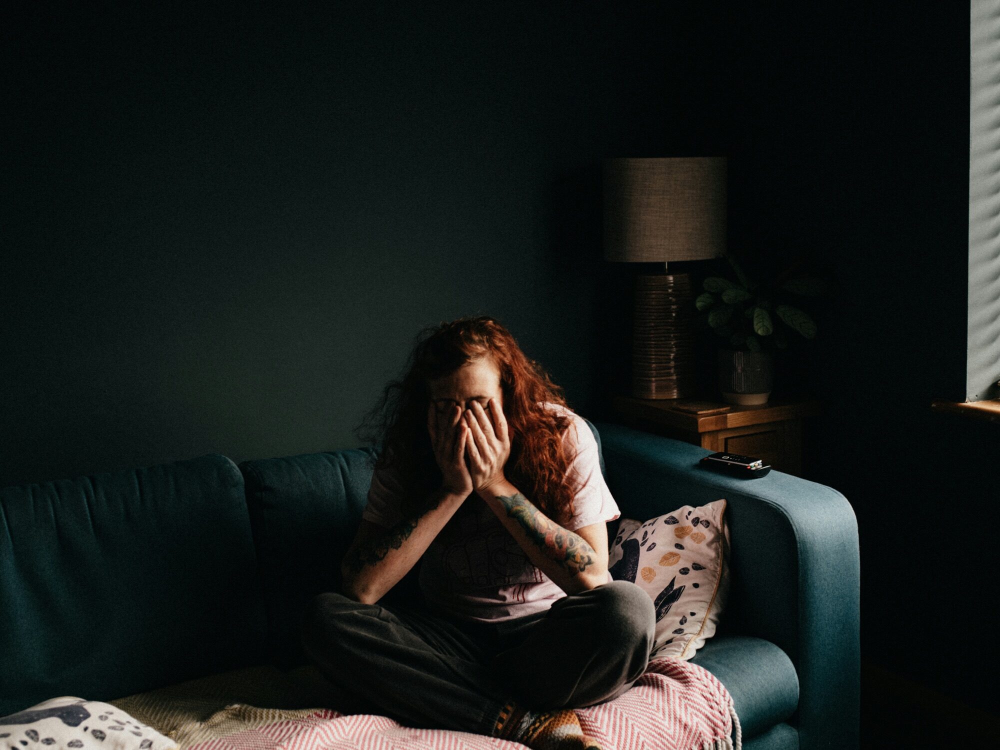 Vrouw met handen voor haar ogen op de bank
